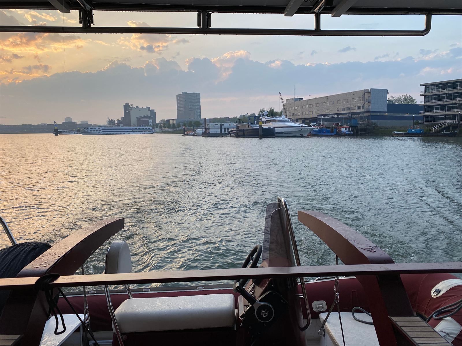 Yachts moored along a harbour quay at dusk, seen from the helm of a tender